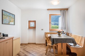 Un coin repas comprenant une table, des chaises, une fenêtre donnant sur un paysage et un tableau accroché au mur.