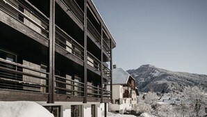 A modern building with multiple balconies, large windows, and a view of snow-covered mountains.
