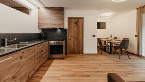 A modern kitchen with wooden cabinets, a built-in oven, and a dining area with a table and chairs.
