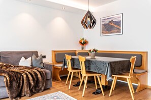 Un salon moderne comprenant un canapé, une table à manger avec des chaises, un banc en bois, un luminaire décoratif et un tableau encadré accroché au mur.