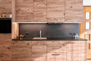 Une cuisine moderne avec des meubles en bois, un évier en acier inoxydable et un four encastré.