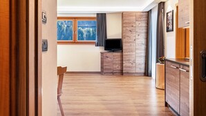 Een moderne keuken met houten kastjes, een ingebouwde televisie en een raam met uitzicht op bomen.