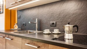 Een moderne keuken met een donker aanrecht, een roestvrijstalen spoelbak en een koffiezetapparaat.
