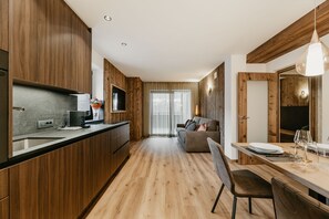 A modern kitchen with wooden cabinets, a dining area with a table and chairs, and a sofa in the background. - Holiday Apartment "Niuasi" with Mountain View, Terrace and Wi-Fi (Ortisei)