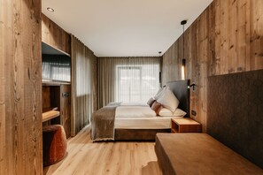 A room with a bed, bedside table, and a wooden wardrobe.