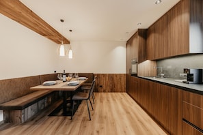 A modern kitchen with wooden cabinetry, a built-in oven, and a dining area with a bench and table.