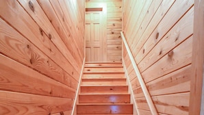 Un escalier en bois, doté d’une rampe, mène à une porte située en haut.