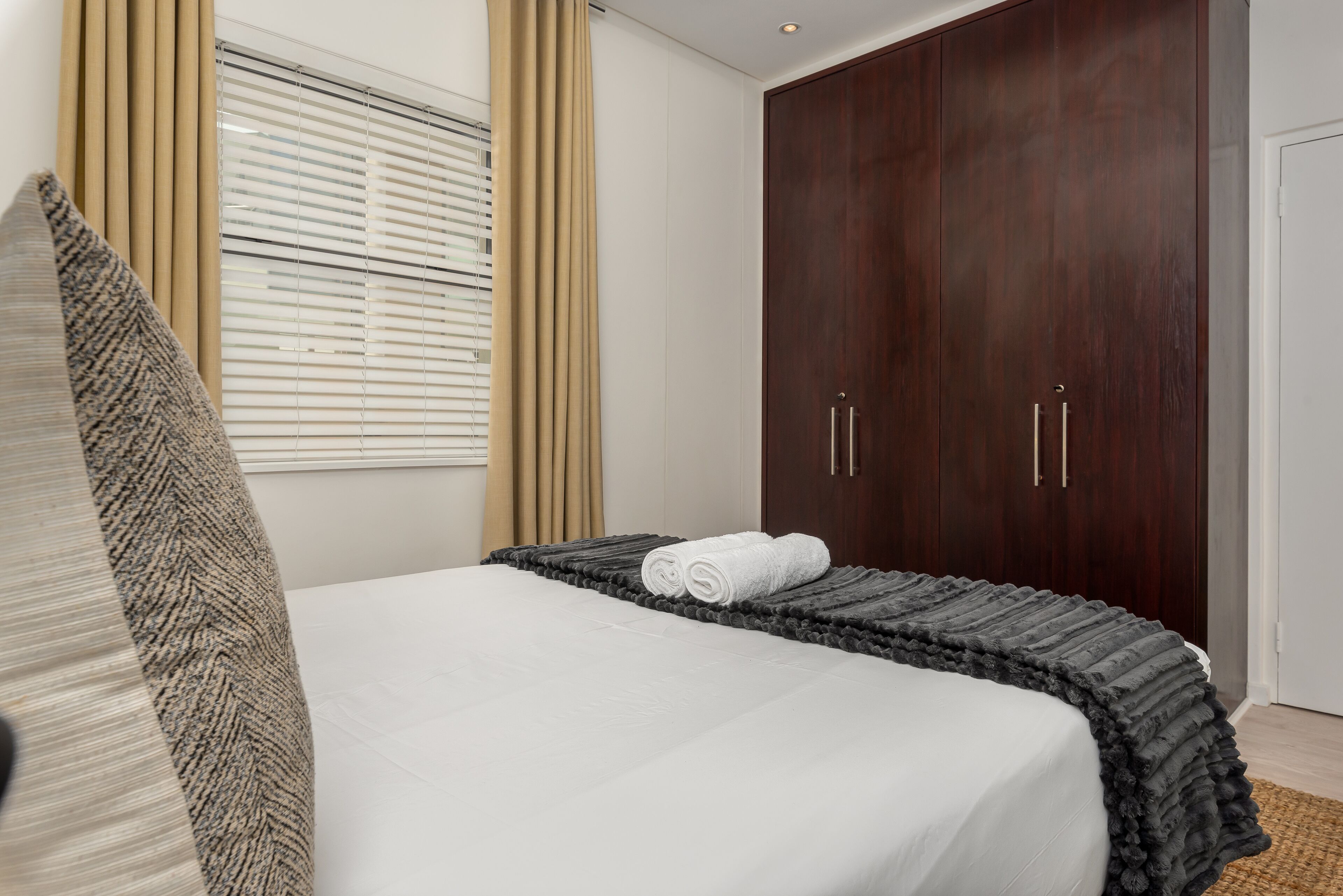 Un dormitorio con cama, un armario amplio y una ventana con persianas.