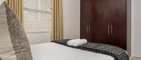 Un dormitorio con cama, un armario amplio y una ventana con persianas.
