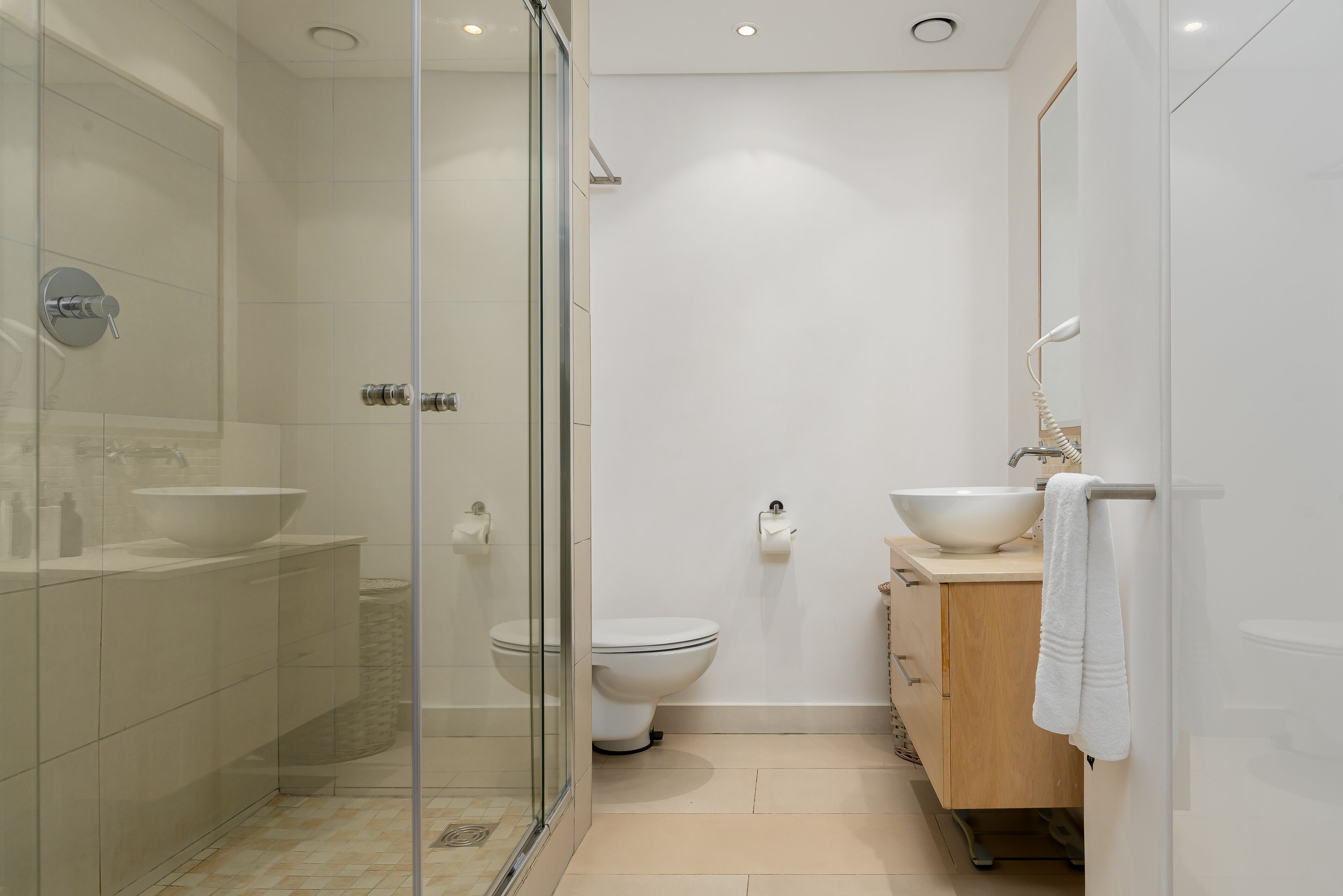 Un baño moderno con cabina de ducha de vidrio, lavamanos blanco y un inodoro.