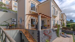 Un immeuble à plusieurs étages doté de balcons, d’un espace extérieur aménagé pour s’asseoir et d’un escalier.