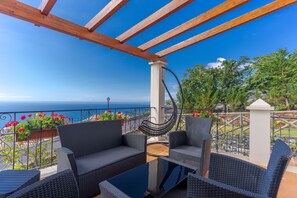 Un balcon doté de meubles en osier et offrant une vue sur la mer.