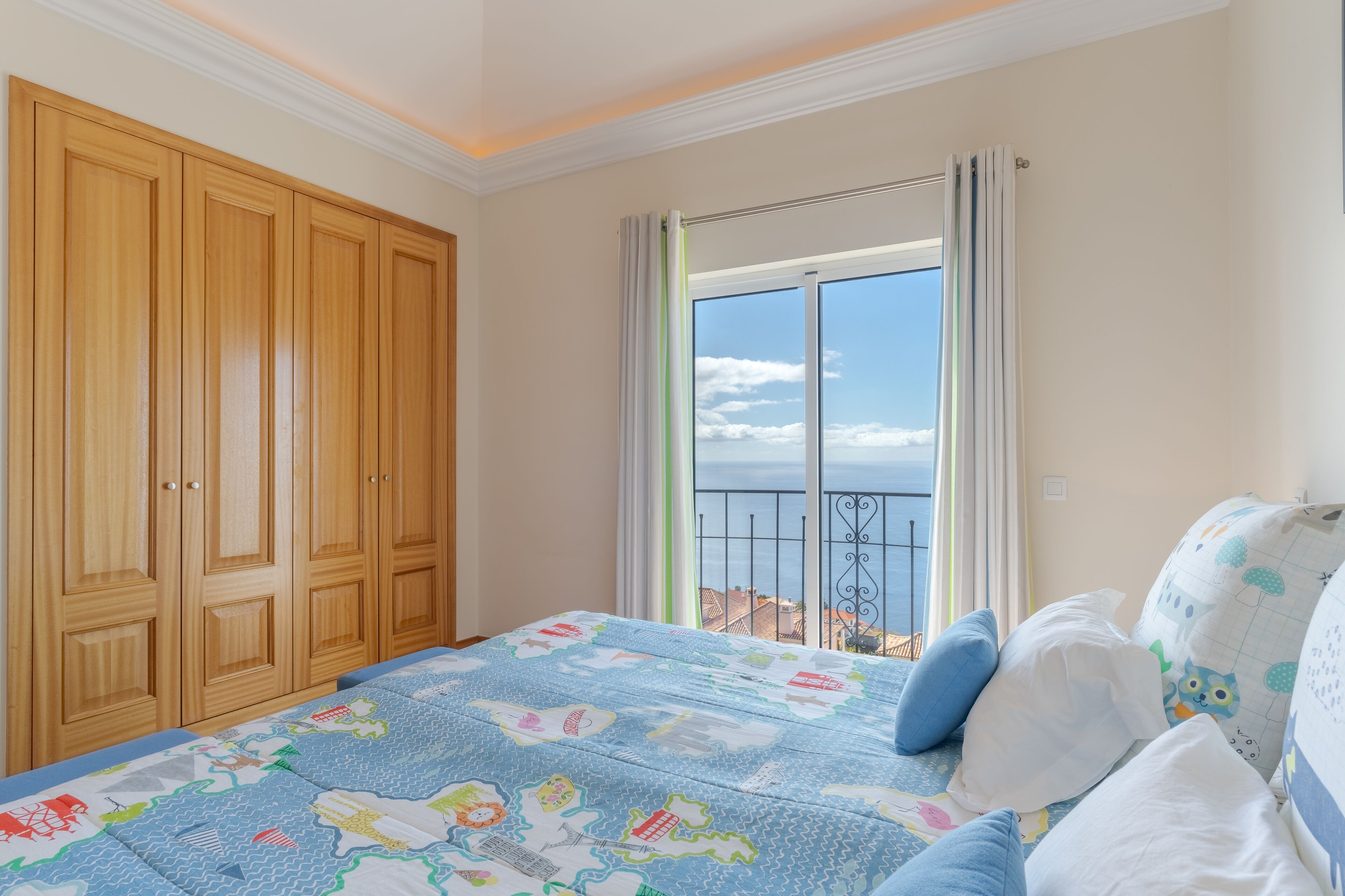 Ein Schlafzimmer mit einem großen Bett, einem Kleiderschrank und einem Balkon mit Blick.