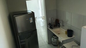 Cocina compacta con refrigerador, estufa, lavamanos y una pequeña encimera.