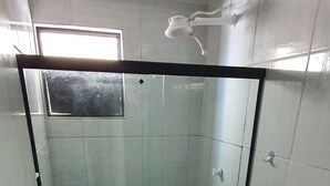 Un baño con ducha de vidrio, inodoro y lavamanos.
