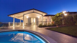 A swimming pool with a covered patio area, a dining table, and a view of the sea. - Villa Ambretta with Private Swimming Pool, Garden and Barbecue (Campagnatico)