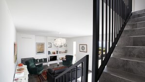 A modern living room with a staircase, a bookshelf, and a green armchair. - Villa Ambretta with Private Swimming Pool, Garden and Barbecue (Campagnatico)