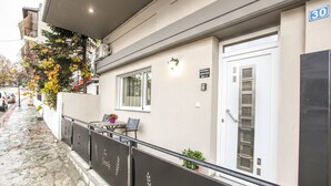 Edifici amb façana blanca, barana de metall negre i una porta amb el número 30.