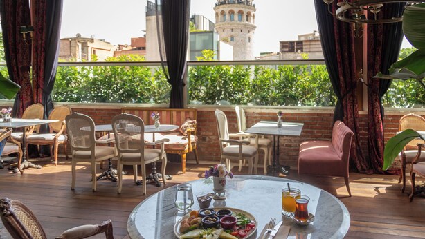 Un restaurant doté d’une terrasse, de tables, de chaises et offrant une vue sur une tour.