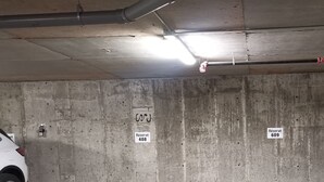A parking garage with concrete walls, a ceiling with exposed pipes, and two signs indicating reserved parking spaces 408 and 609.