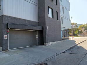 Un edificio con una puerta de garaje cerrada, un letrero de no estacionamiento y un hidrante en la acera.