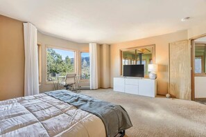 A hotel room with a bed, a TV, a desk, and a view of the outdoors. - Luxury Retreat | Hot Tub, Sauna, Gym | Manitou (Manitou Springs)