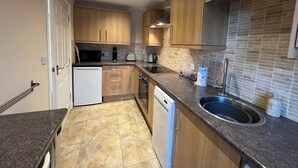 Een moderne keuken met houten kastjes, een vaatwasser, een spoelbak en een magnetron.