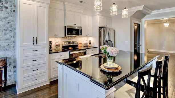 A modern kitchen with white cabinetry, a central island, stainless steel appliances, and pendant lighting.