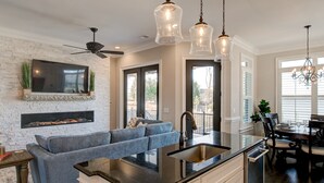 A modern kitchen with a built-in island, a fireplace, and a dining area with a chandelier.