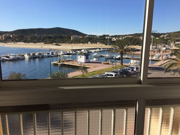 A marina with boats, a beach, and a view of a hilly landscape.