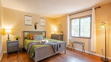 A bedroom with a bed, nightstands, a floor lamp, and a window with curtains.