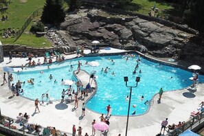 Ein großer Pool im Freien, umgeben von einer Betonplattform, mit einem felsigen Hintergrund.