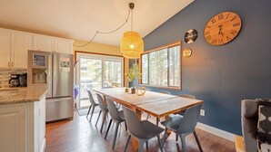 Una cocina moderna con una mesa y sillas de madera, un refrigerador empotrado y un ventanal con vistas al exterior.