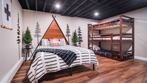 A bedroom with a bed, a bunk bed, and a wall with a geometric design. - Hot Tub, Game Room, BBQ & Playhouse Oasis – Family Retreat, 5mins to Lake! (Hawley)