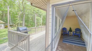 A covered porch with a grill, two Adirondack chairs, and a small table. - Hot Tub, Game Room, BBQ & Playhouse Oasis – Family Retreat, 5mins to Lake! (Hawley)
