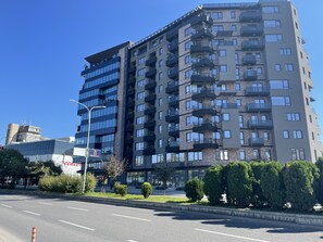 Un immeuble à plusieurs étages doté de balcons, un ciel dégagé et une rue au premier plan.