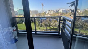 A balcony with a view of a cityscape, including buildings and a crane.