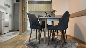 A modern kitchen with wooden cabinets, a dining table with four chairs, and a small decorative vase with flowers.