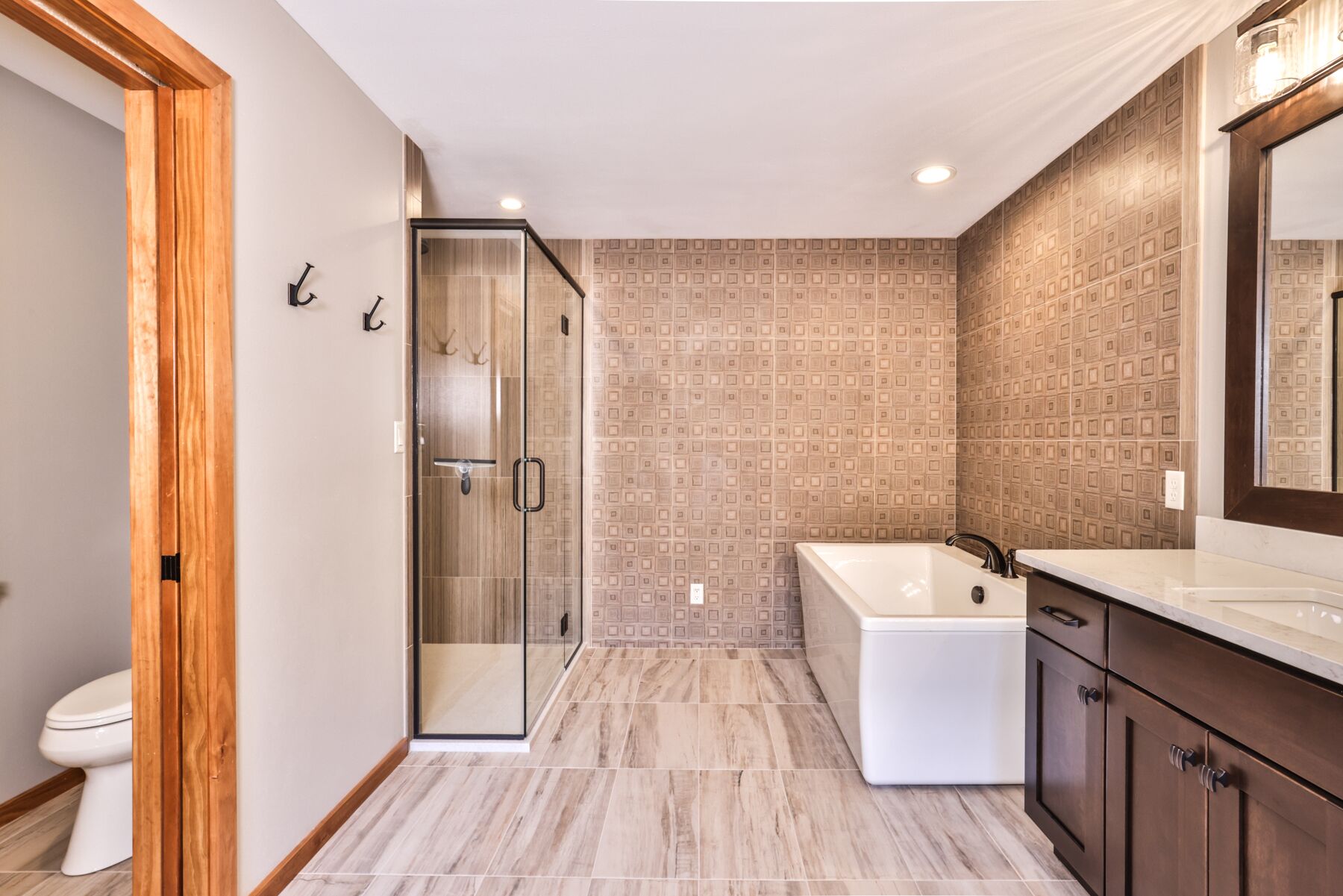A modern bathroom with a glass shower enclosure, a freestanding bathtub, and a large mirror above the sink.