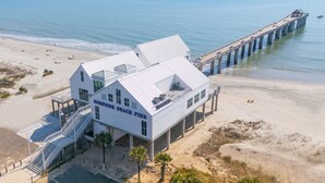 Un alojamiento frente a la playa con un gran edificio blanco que indica “SURFSIDE BEACH PIER”.