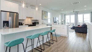 Una cucina moderna con mobili bianchi, elettrodomestici in acciaio inossidabile e un'isola centrale con sgabelli da bar.