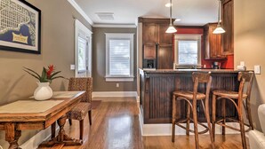 A kitchen with wooden cabinets, a bar area, and a dining table with chairs. - Hyde Park Luxury Studio w/ Prime Location! (Tampa)