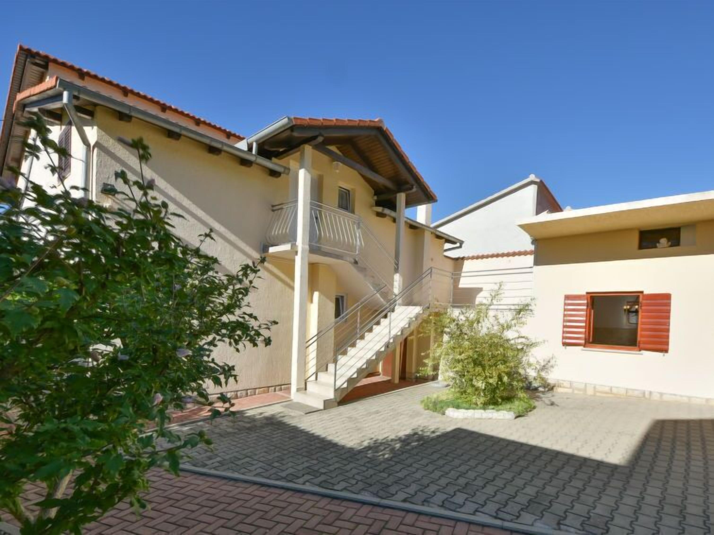 A residential building with a central staircase, a balcony, and a small garden area.