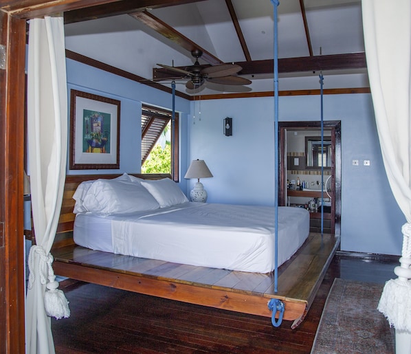 A bedroom with a bed, a ceiling fan, a window, and a painting on the wall. - Amazing 4 BR Villa with fantastic views- 3 min from the beach! (Cap Estate)