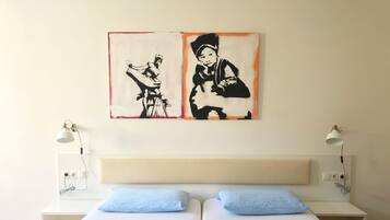 A hotel room with two beds, a large painting on the wall, bedside lamps, and a white headboard.