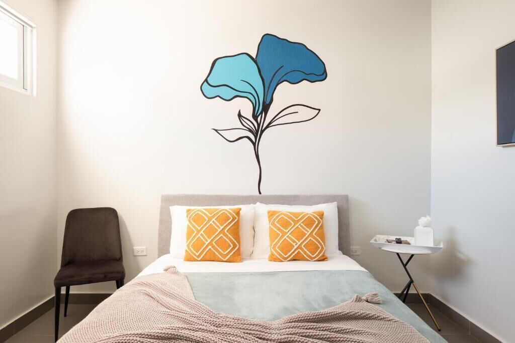 Una camera d'albergo con un letto, due cuscini, una sedia, un comodino e un elemento decorativo a parete.