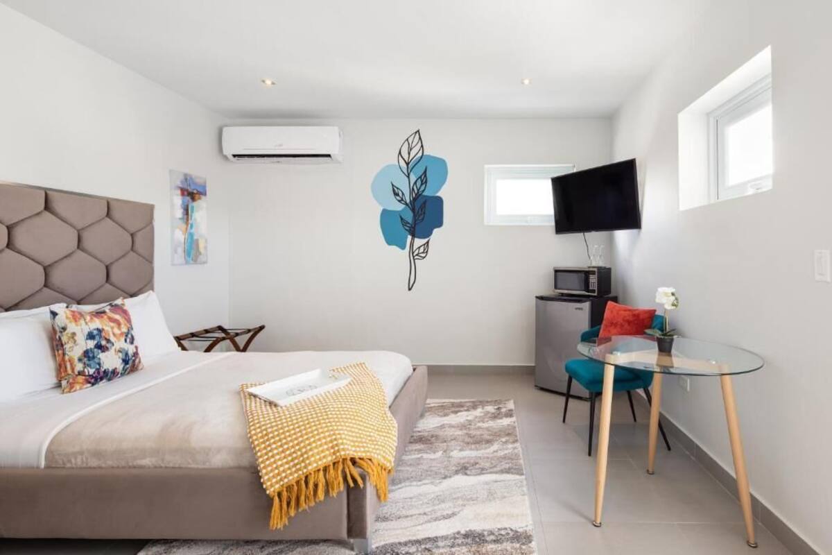 A modern bedroom with a bed, a desk, a television, and a decorative wall sticker.