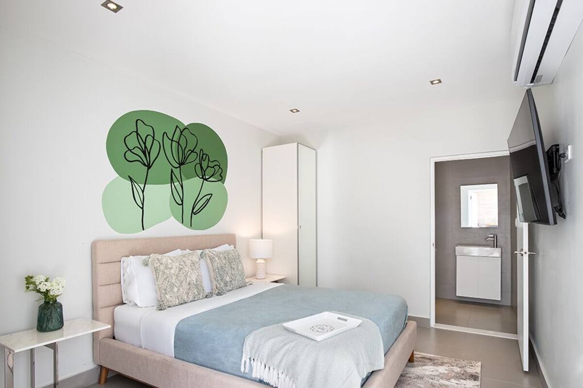 A modern bedroom with a bed, bedside table, and a wall-mounted TV.