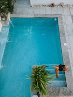Piscina rectangular con agua azul cristalina, rodeada por una terraza de piedra.