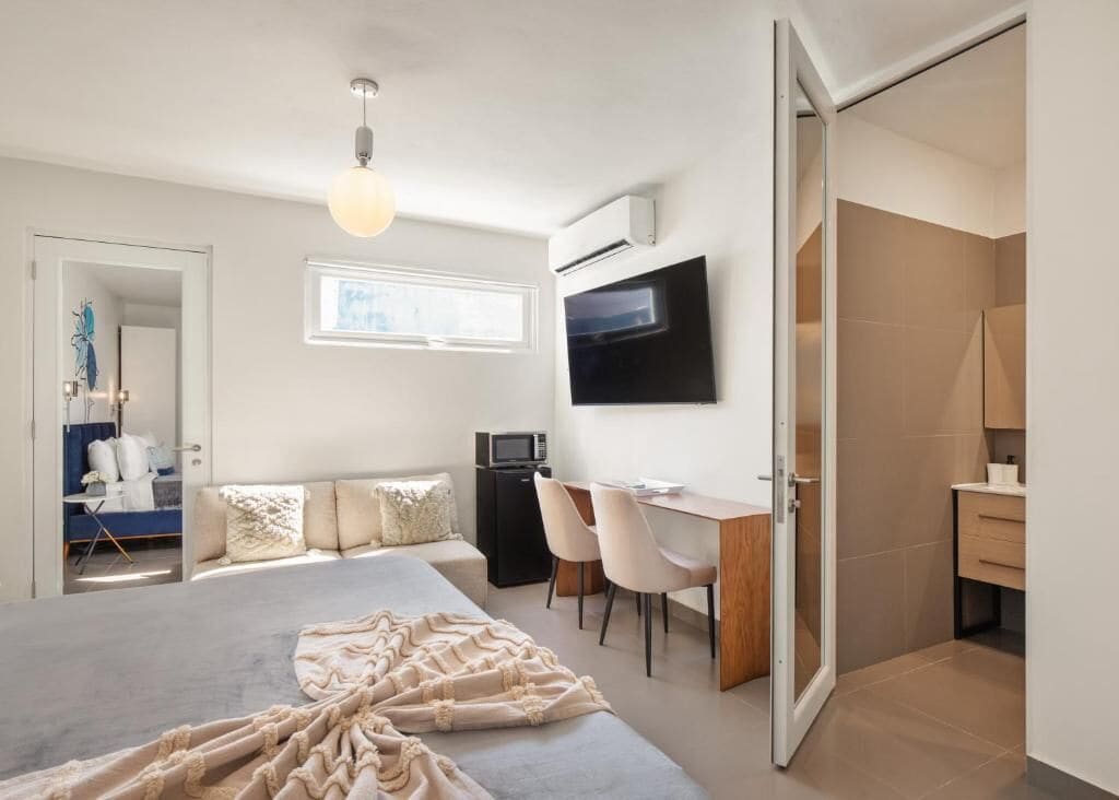 A modern bedroom with a large bed, a desk, and a TV.